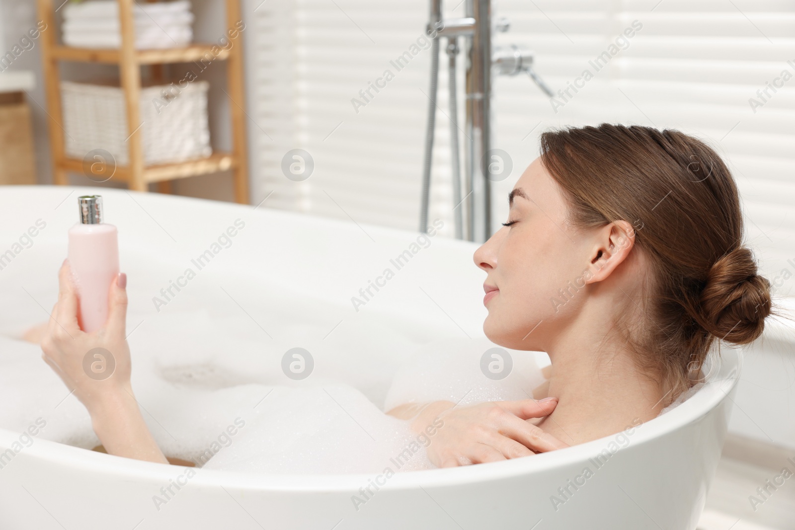 Photo of Woman taking bath with shower gel in bathroom