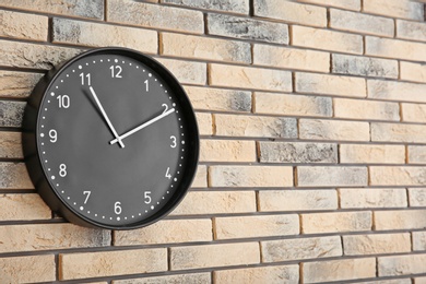Photo of Stylish clock on brick wall. Time concept