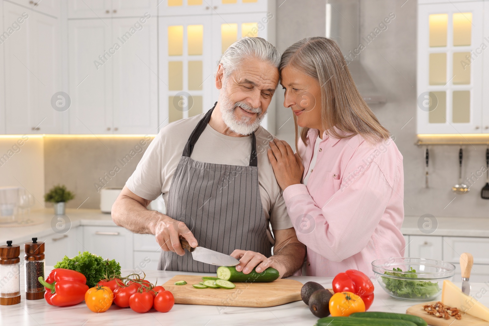 Photo of Affectionate senior couple cooking together in kitchen