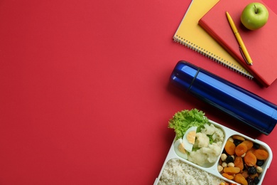 Flat lay composition with thermos and food on red background. Space for text