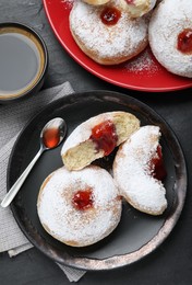 Photo of Delicious jelly donuts served with coffee on black table, flat lay