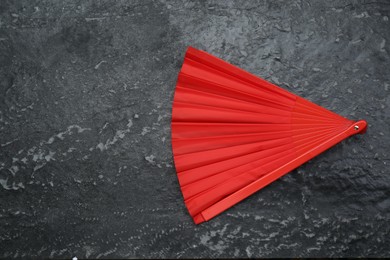 Photo of Bright red hand fan on grey textured background, top view. Space for text