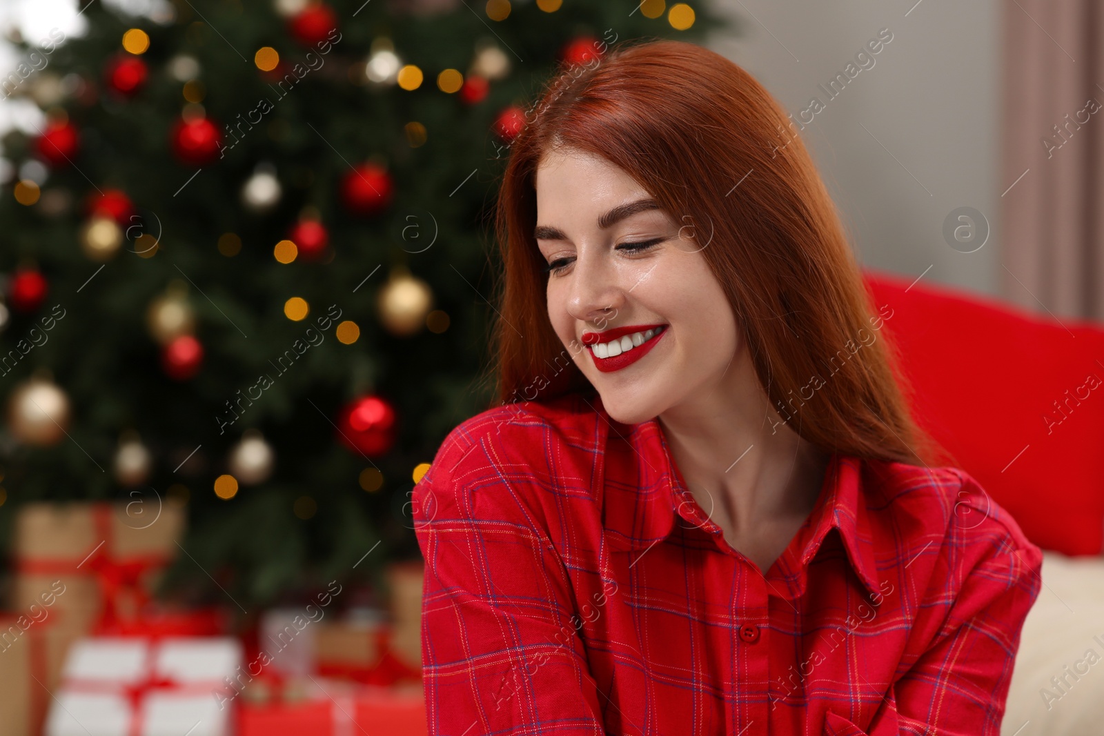 Photo of Beautiful young woman near Christmas tree indoors, space for text