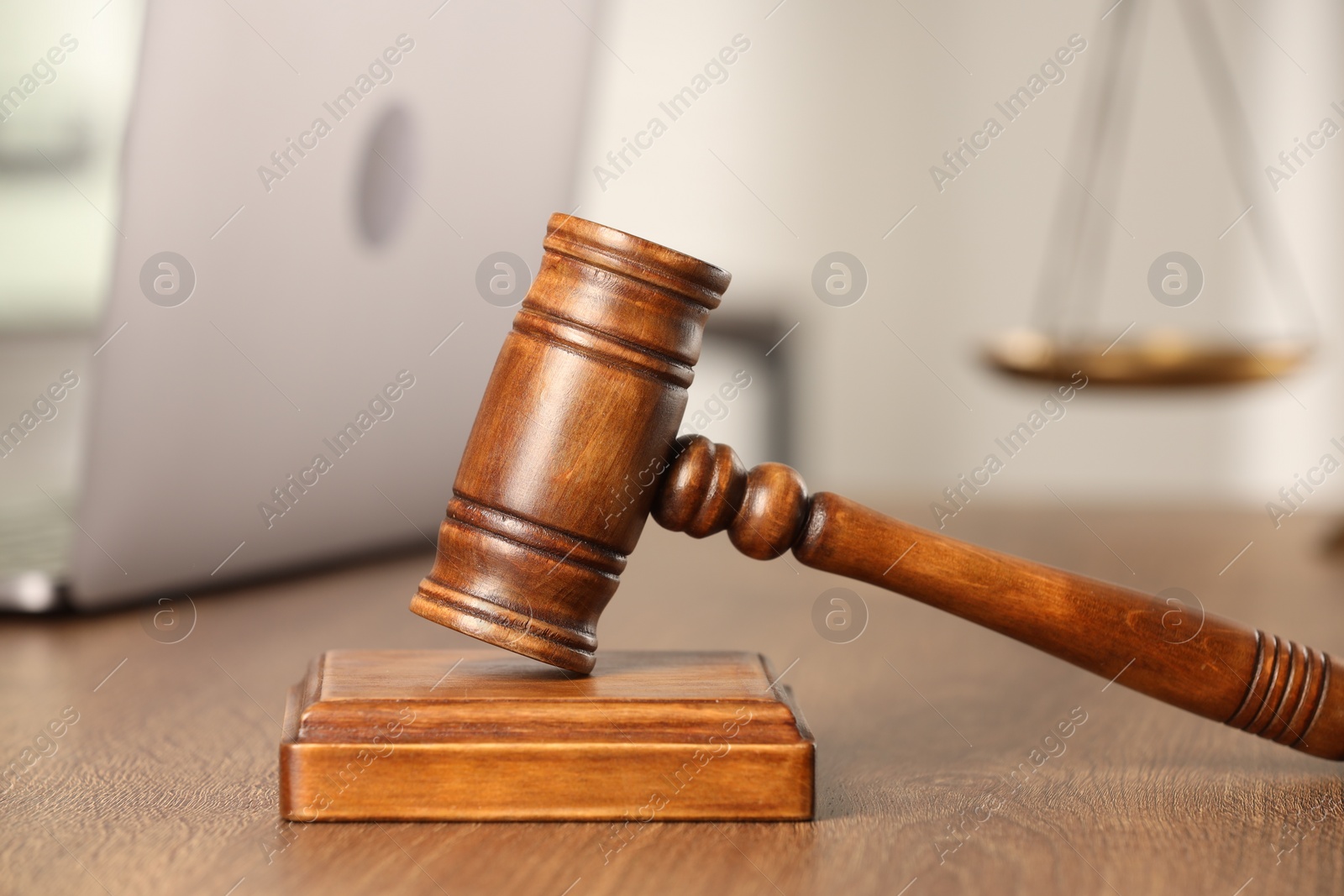 Photo of Law concept. Gavel and laptop on wooden table, closeup