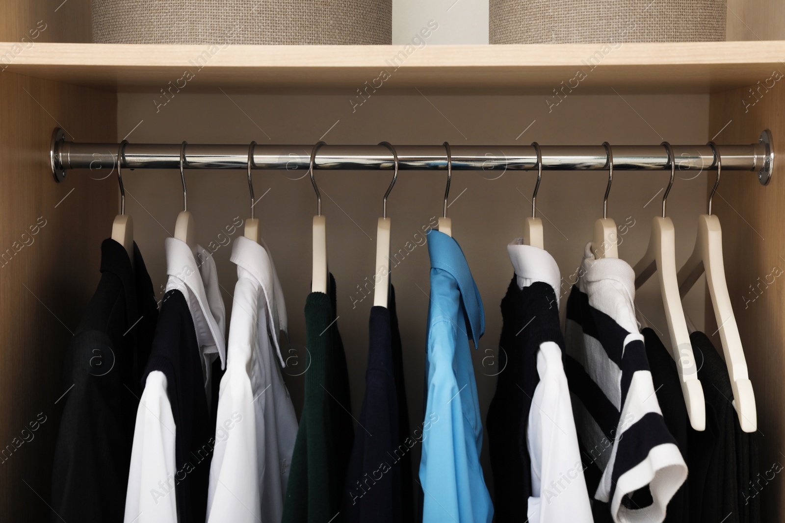 Photo of Hangers with teenage clothes on rack in wardrobe, closeup