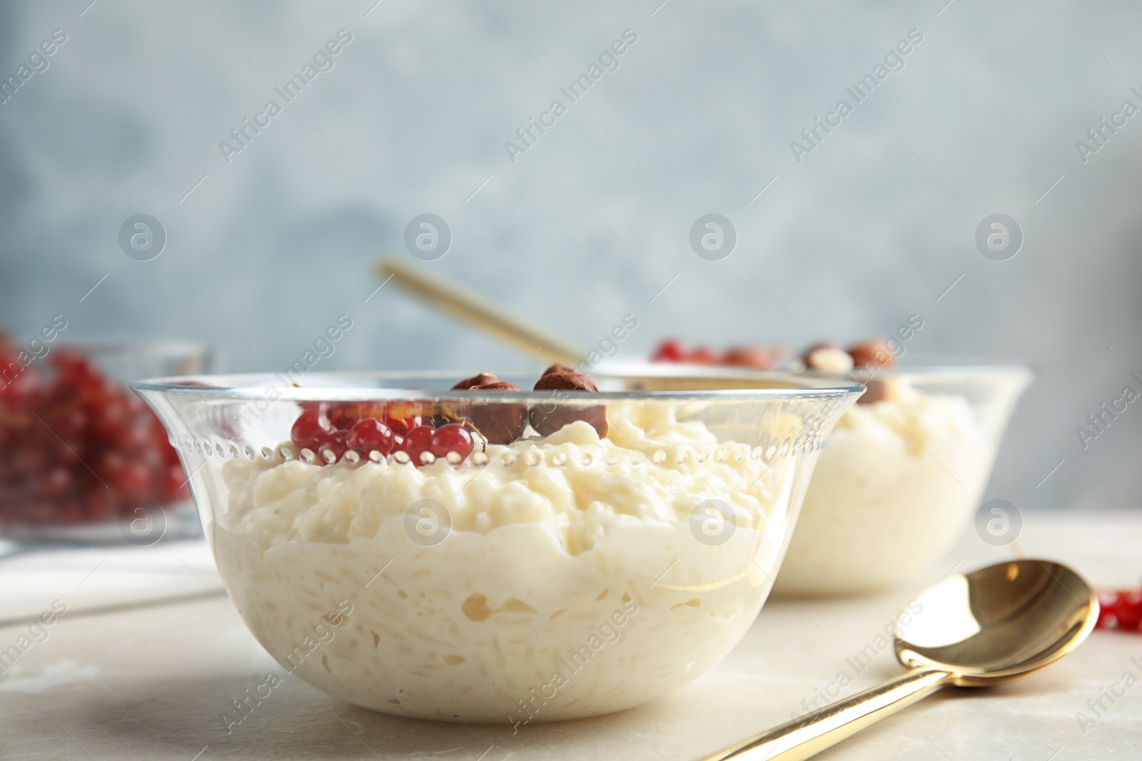 Photo of Creamy rice pudding with red currant and hazelnuts in bowl served on table