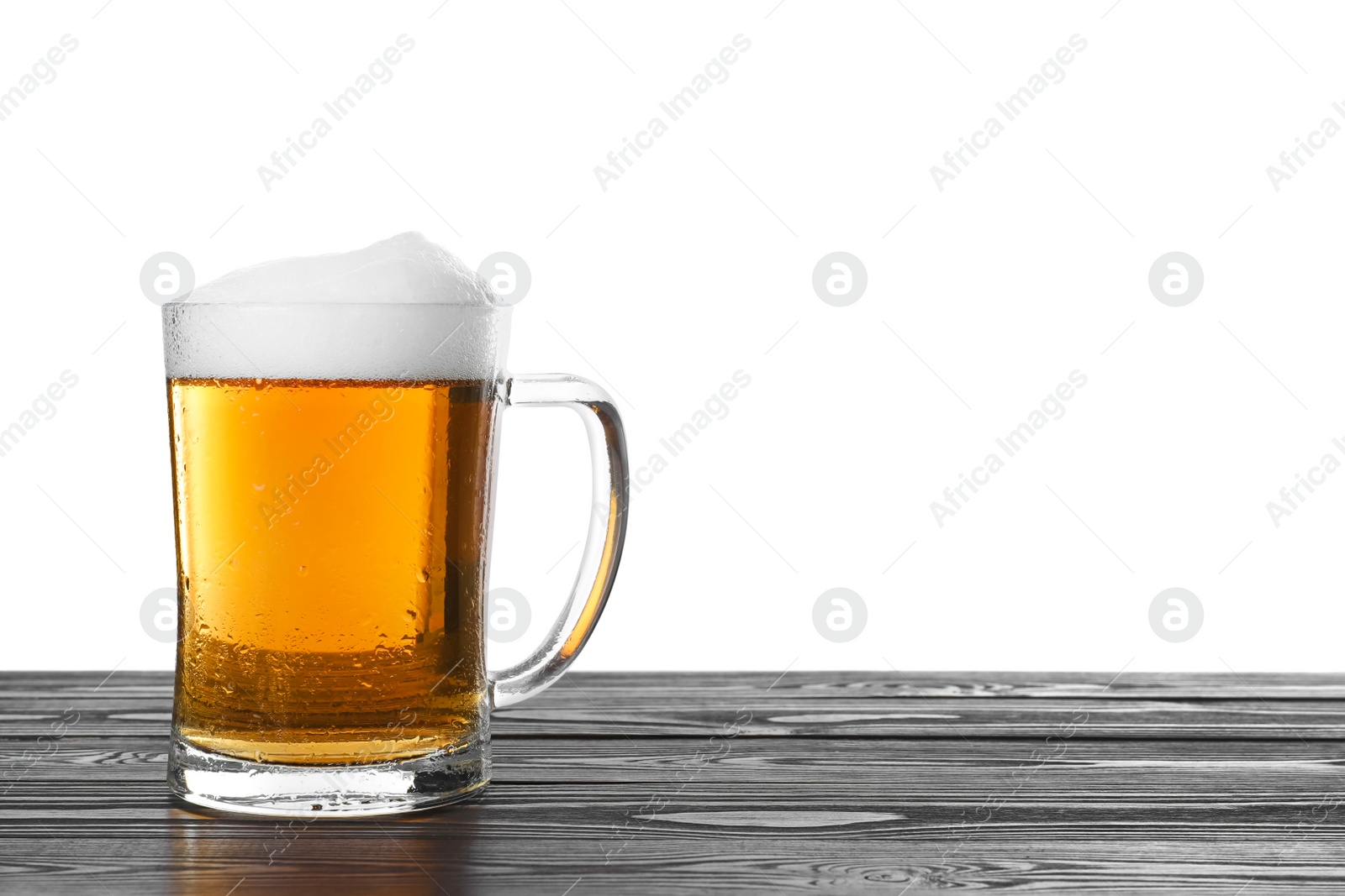 Photo of Glass mug of tasty beer on black wooden table against white background