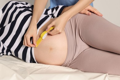 Pregnant woman visiting physiotherapist. Doctor applying kinesio tape on couch, closeup