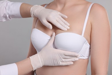 Photo of Mammologist checking woman's breast on gray background, closeup