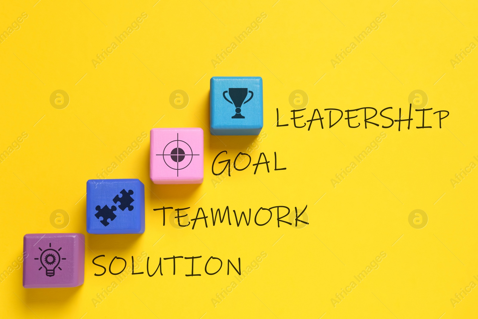 Image of Colorful cubes with different images and words Leadership, Goal, Teamwork and Solution on yellow background, flat lay