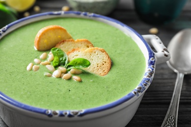 Bowl of healthy green soup with fresh spinach on grey wooden table, closeup