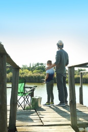 Photo of Father and son fishing together on sunny day. Space for text