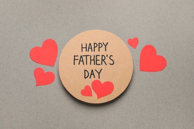 Greeting card with phrase Happy Father's Day and paper hearts on grey background, flat lay