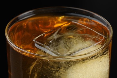 Photo of Tasty whiskey and ice in glass on black background, closeup