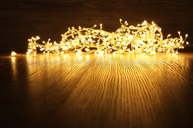 Photo of Beautiful glowing Christmas lights on wooden table. Space for text