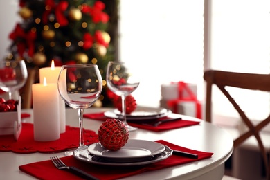 Photo of Festive table setting and Christmas tree in stylish room interior