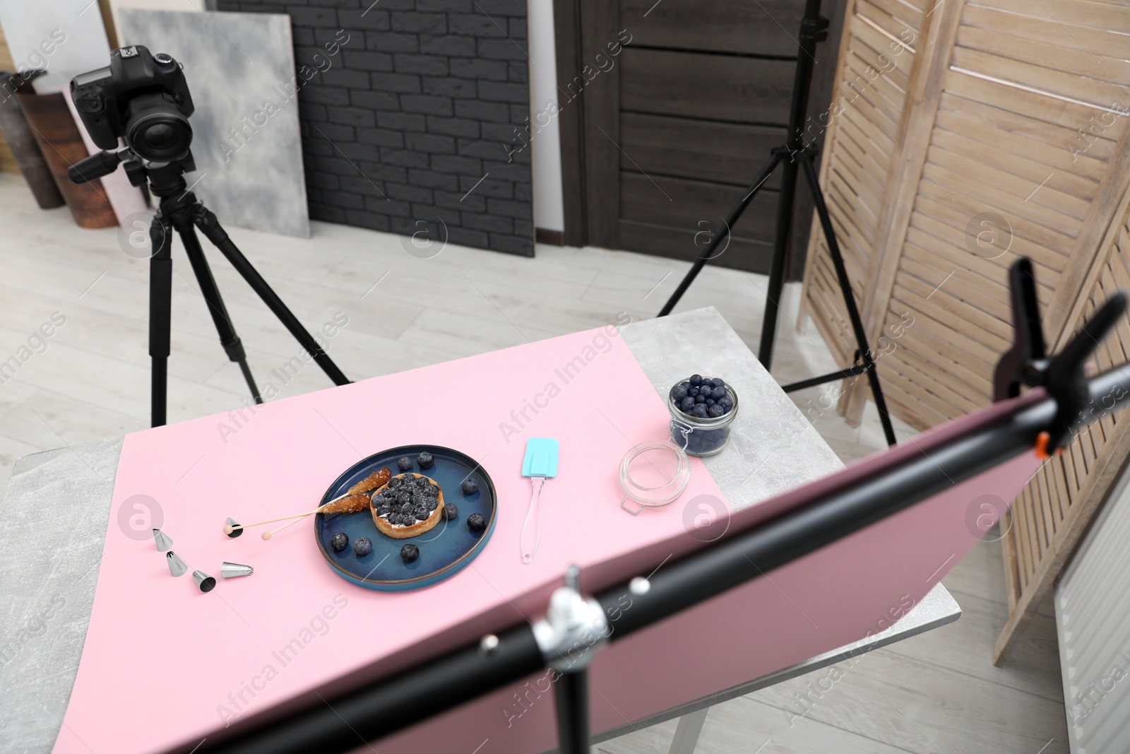 Photo of Professional equipment and composition with delicious dessert on pink background in studio, above view. Food photography