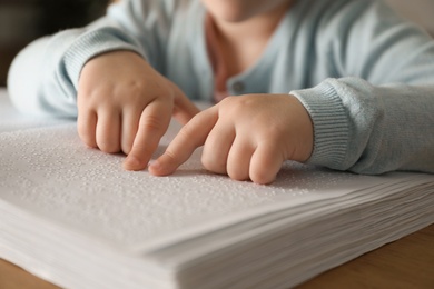 Photo of Blind child reading book written in Braille, closeup