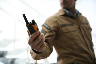 Professional security guard with portable radio set indoors, closeup