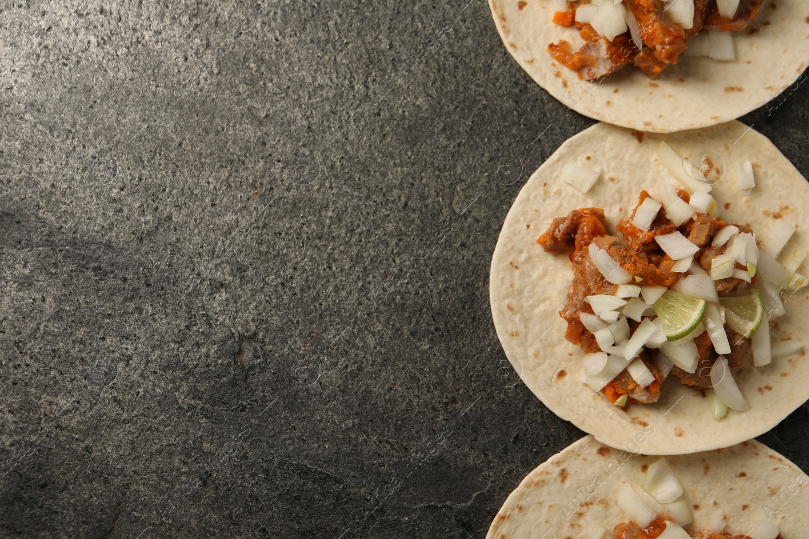 Photo of Delicious tacos with vegetables, meat and lime on grey textured table, flat lay. Space for text