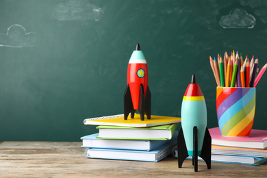 Photo of Bright toy rockets and school supplies on wooden table