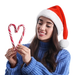 Photo of Beautiful woman in Santa Claus hat making heart with candy canes on white background
