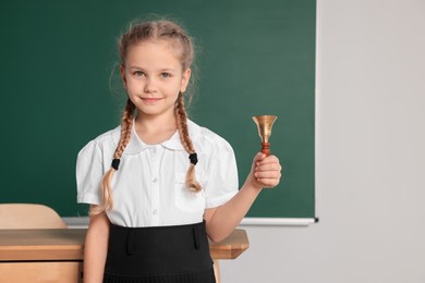 Photo of Pupil with school bell near chalkboard in classroom