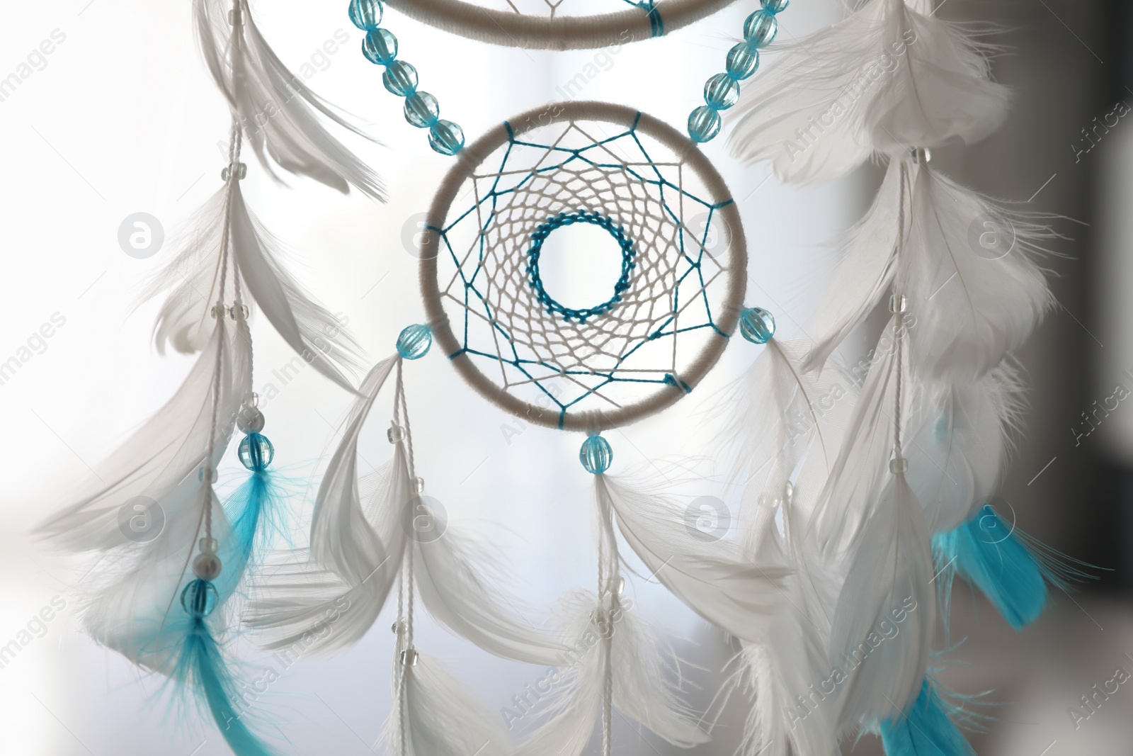 Photo of Beautiful dream catcher hanging against blurred background, closeup