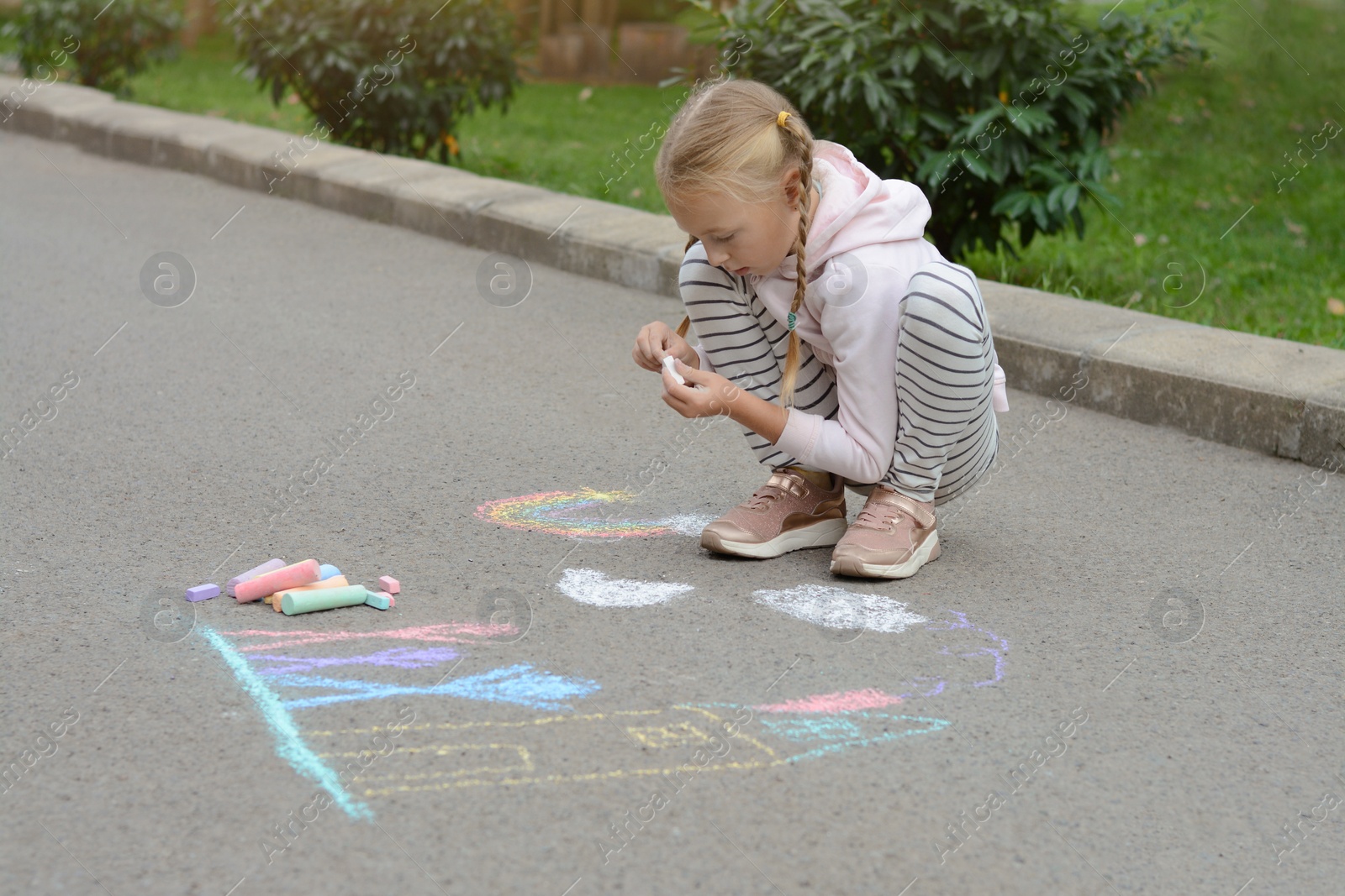 Photo of Little child drawing her hands with chalk outdoors