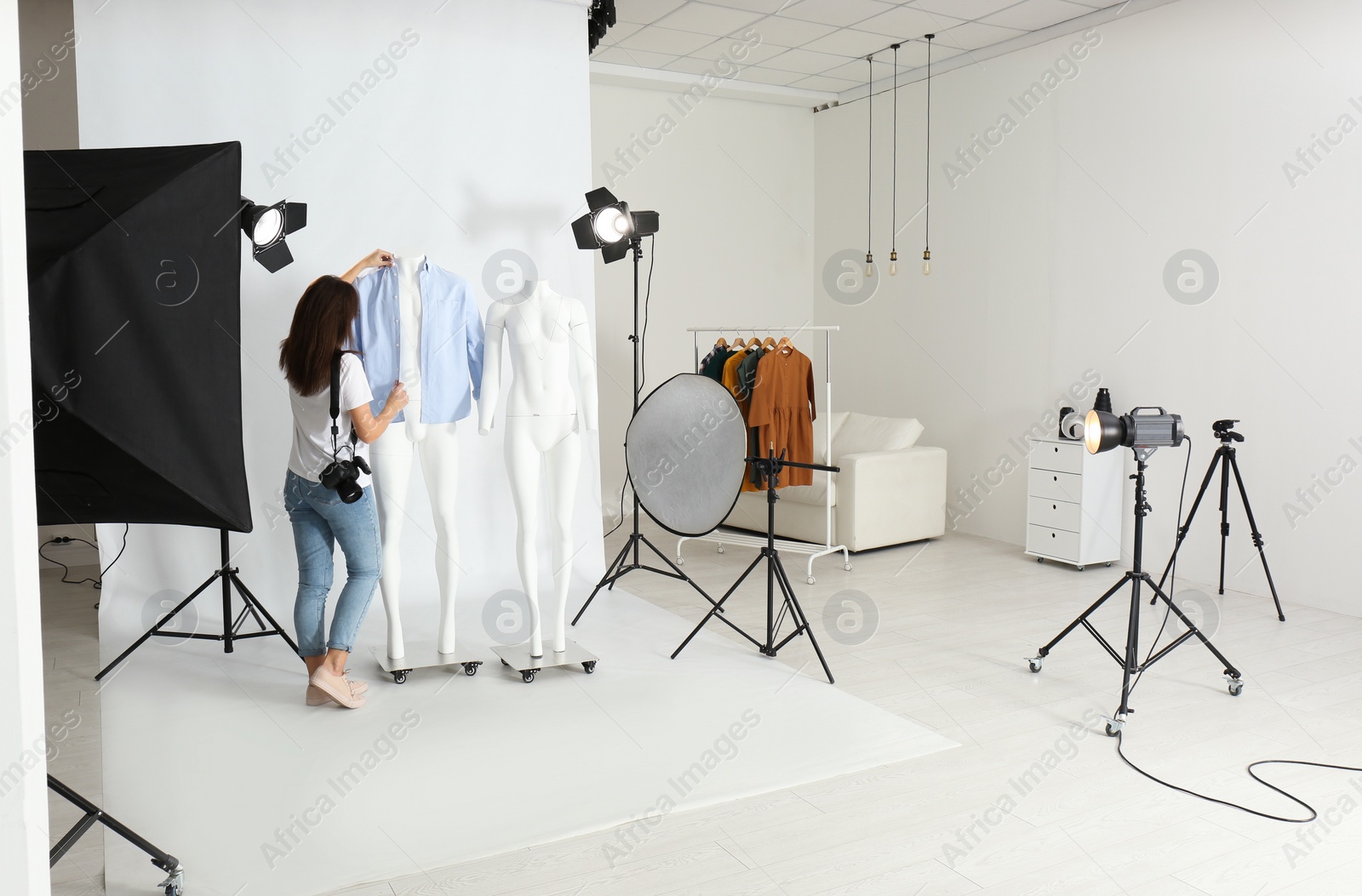 Photo of Woman putting clothes on ghost mannequins in professional photo studio