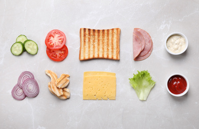 Fresh ingredients for tasty sandwich on grey marble background, flat lay