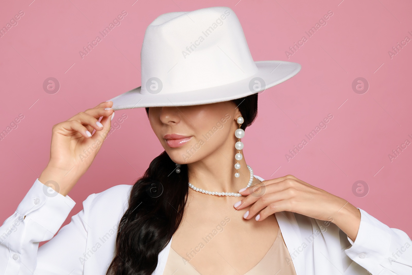 Photo of Young woman wearing elegant pearl jewelry on pink background