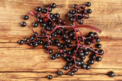Photo of Black elderberries (Sambucus) on wooden table, flat lay
