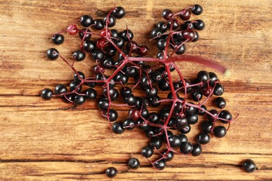 Black elderberries (Sambucus) on wooden table, flat lay