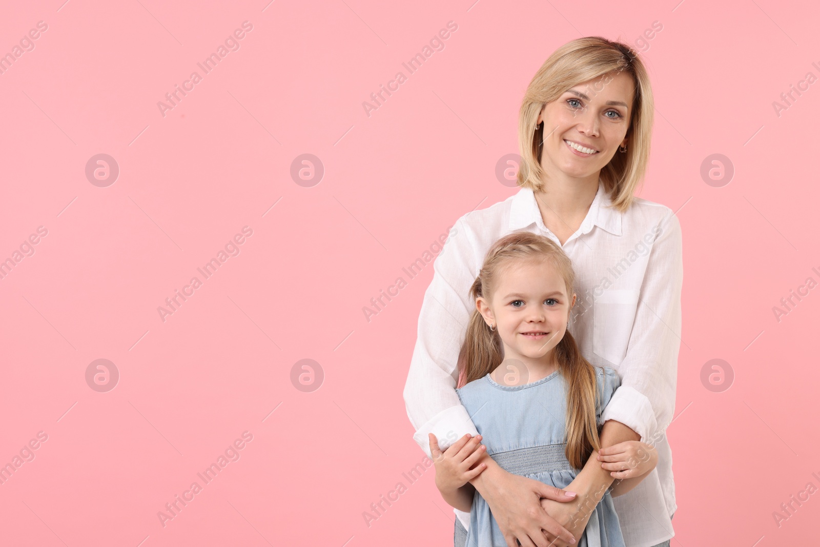 Photo of Family portrait of happy mother and daughter on pink background. Space for text