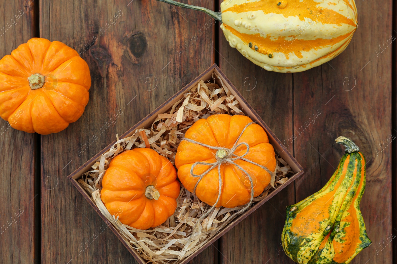 Photo of Crate and ripe pumpkins on wooden table, flat lay