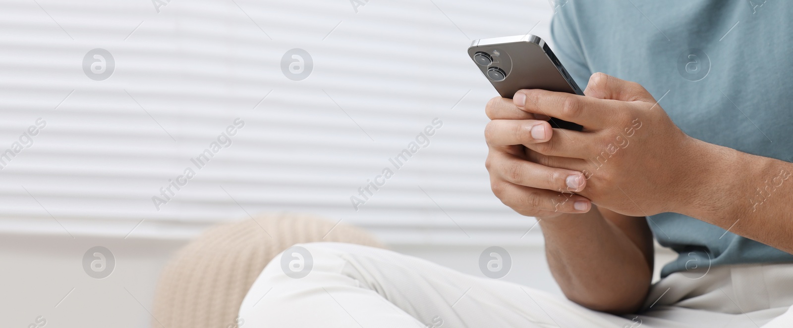 Image of Man typing message on mobile phone indoors, closeup. Banner design with space for text