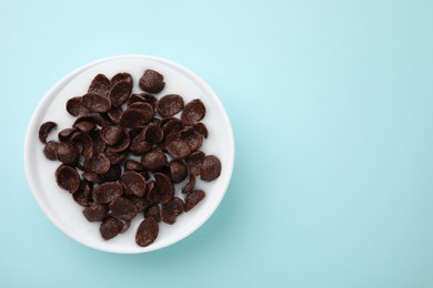 Photo of Breakfast cereal. Chocolate corn flakes and milk in bowl on turquoise background, top view. Space for text