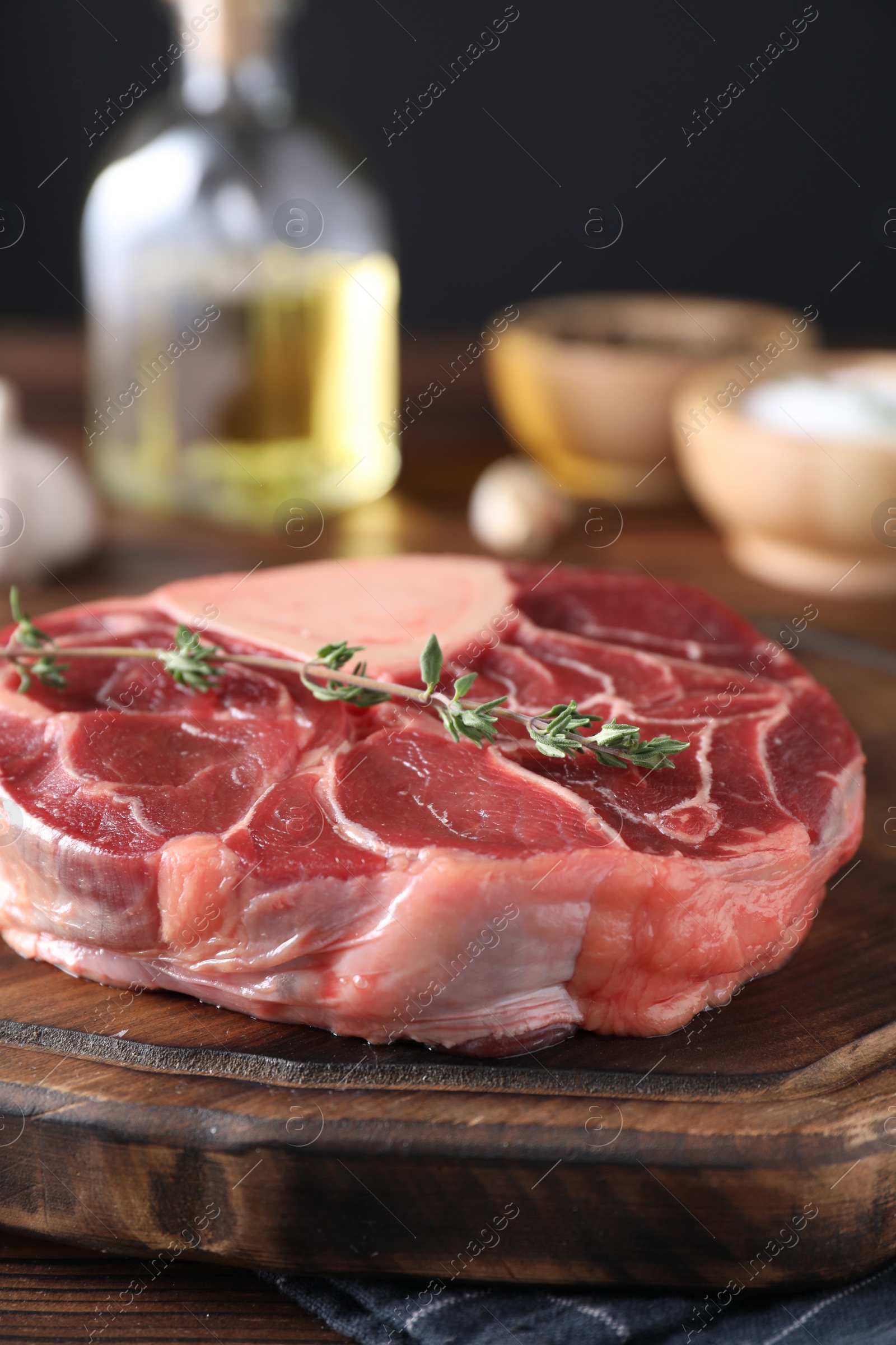 Photo of Piece of raw beef meat and thyme on wooden table, closeup