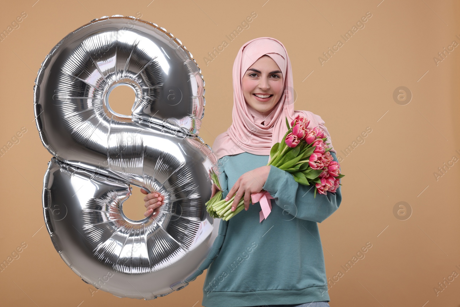 Photo of Happy Women's Day. Woman in hijab with beautiful bouquet and balloon in shape of number 8 on beige background