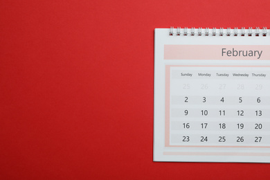 Photo of February calendar on red background, top view. Space for text