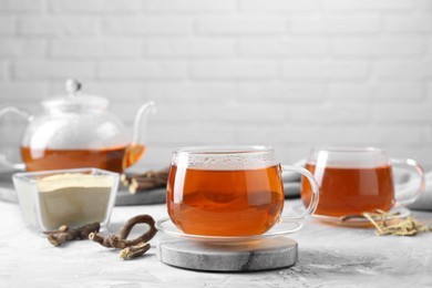 Aromatic licorice tea, powder and dried sticks of licorice root on light gray textured table. Space for text