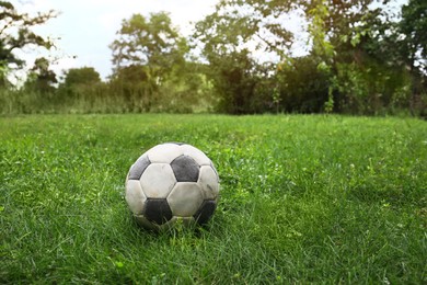 Photo of Dirty soccer ball on fresh green grass outdoors