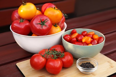 Photo of Bowls with fresh tomatoes and spices on wooden table