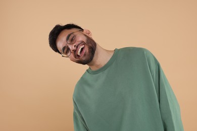 Photo of Handsome young man laughing on beige background