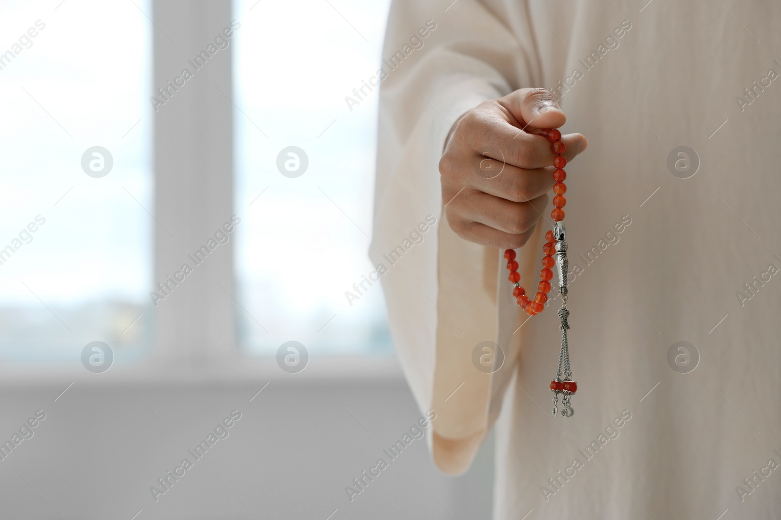 Photo of Muslim man with misbaha indoors, closeup. Space for text