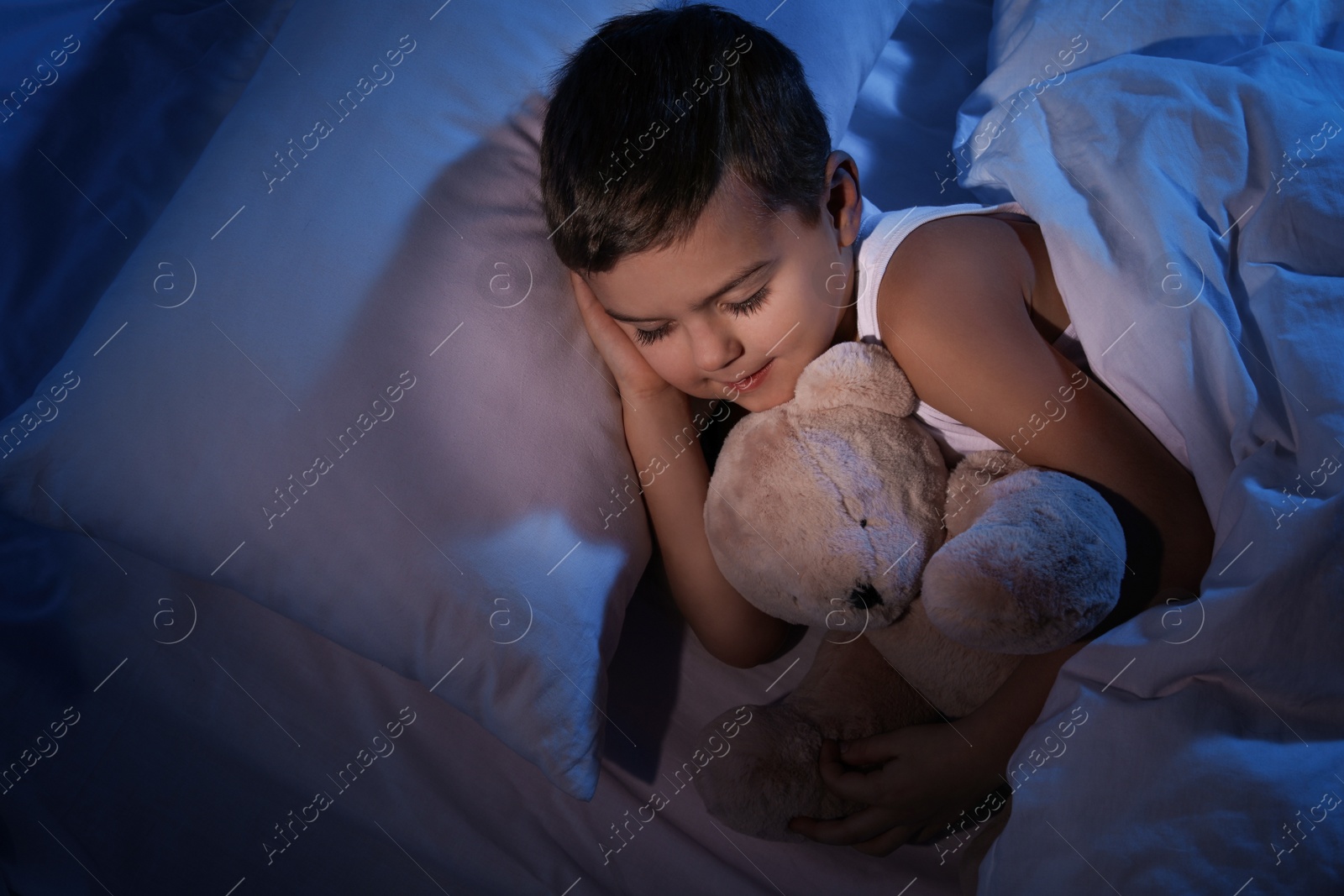 Photo of Little boy sleeping with teddy bear at home. Bedtime