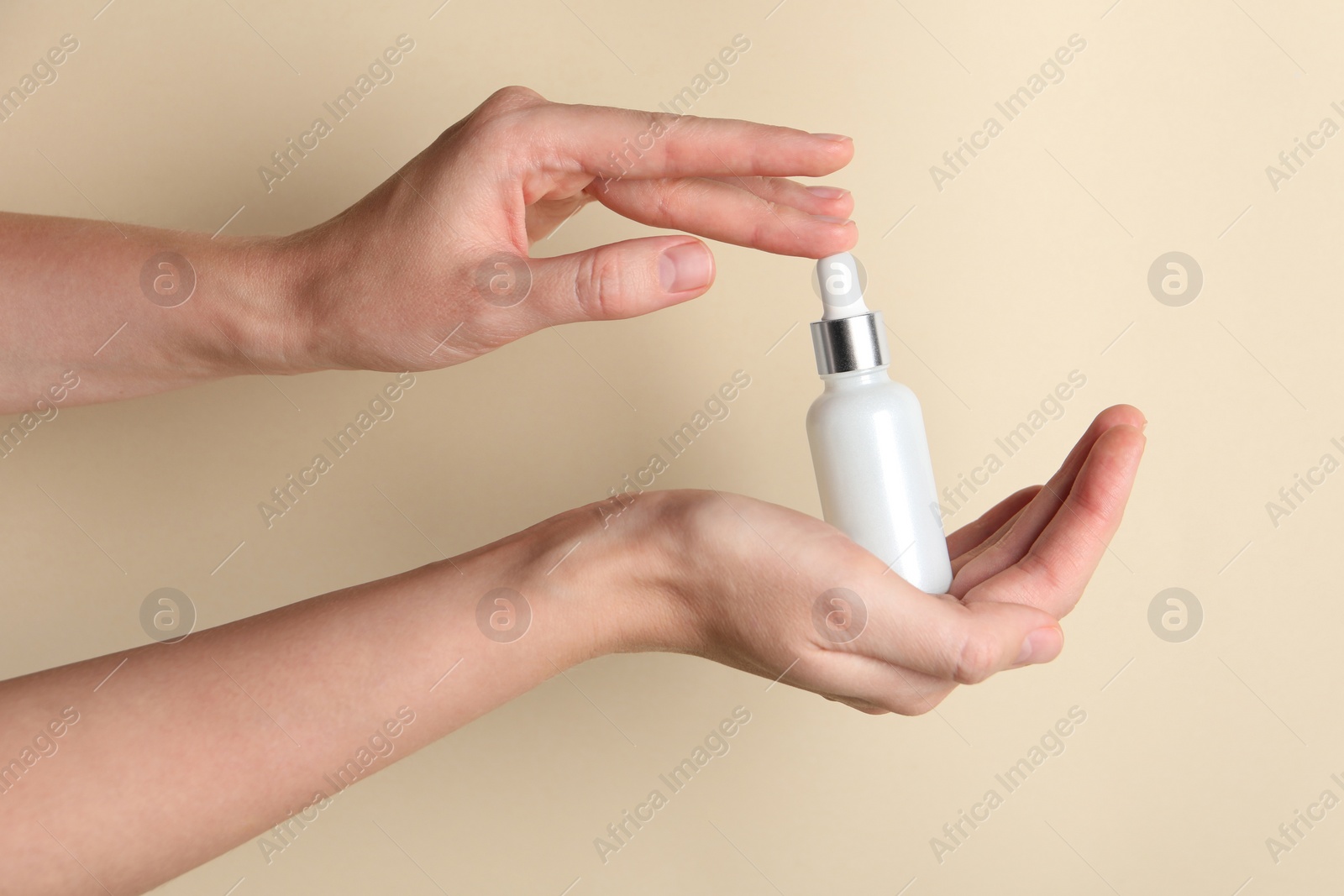 Photo of Woman with bottle of cosmetic serum on beige background, closeup