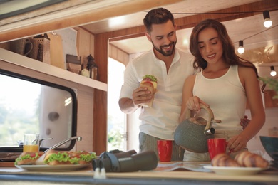 Photo of Happy young couple having breakfast in trailer. Camping vacation