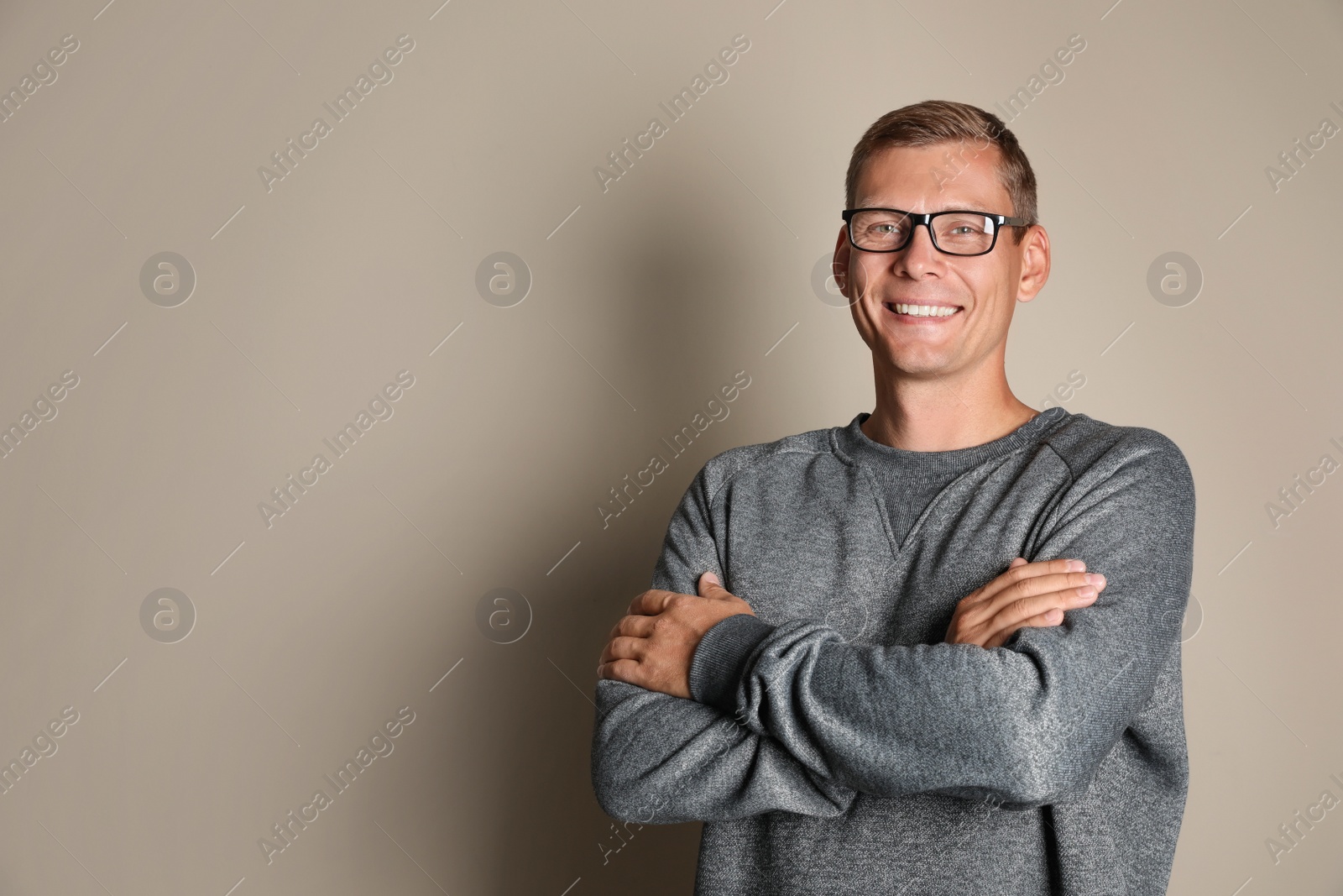 Photo of Man in stylish grey sweatshirt on beige background, space for text